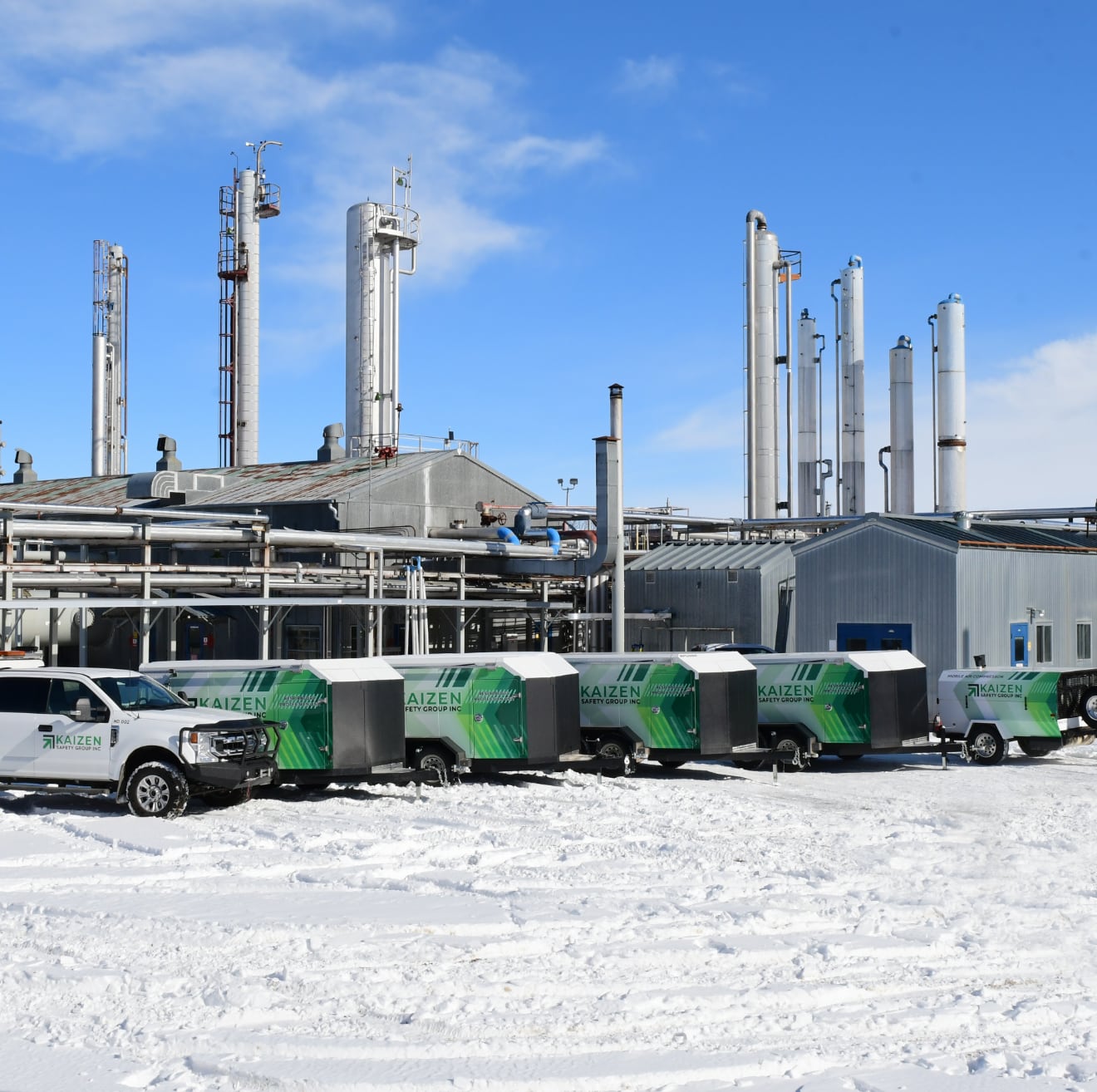 White truck and multiple utility trailers at work site in winter